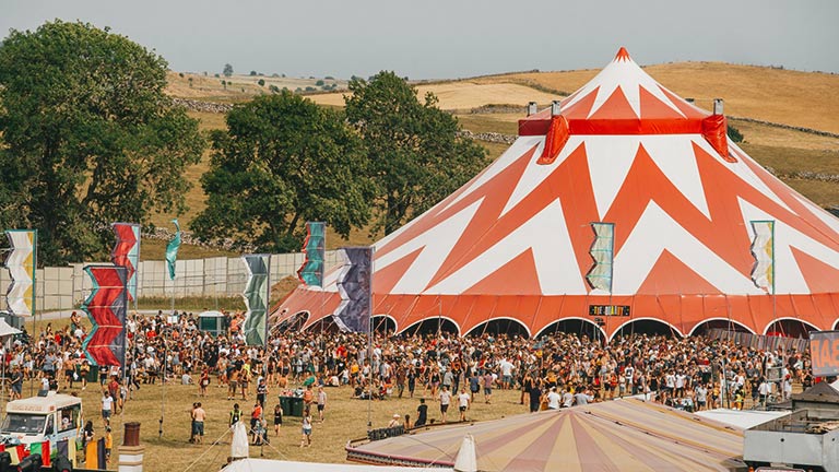 A big red and white tent and festival-goers with a hilly backdrop at Y Not Festival