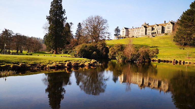 The beautiful face of Bovey Castle mirrored in a glassy lake