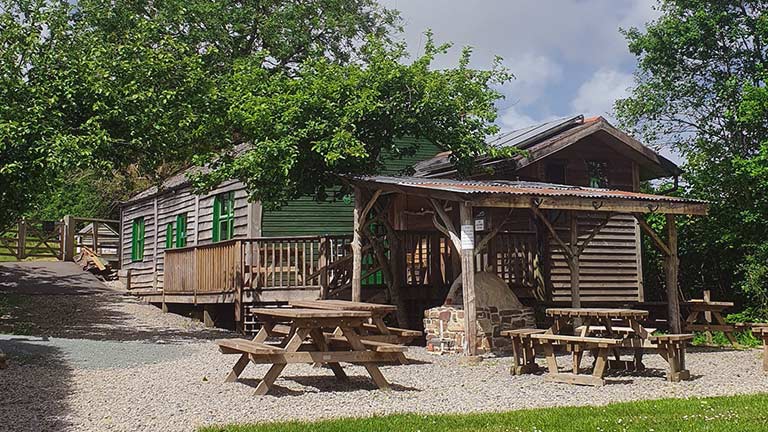 A pretty view of Yarde Orchard Cafe in Peters Marland surrounded by trees and bathed in sunshine