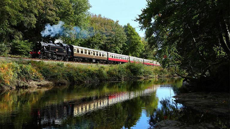 A steam train running alongside a river in South Devon