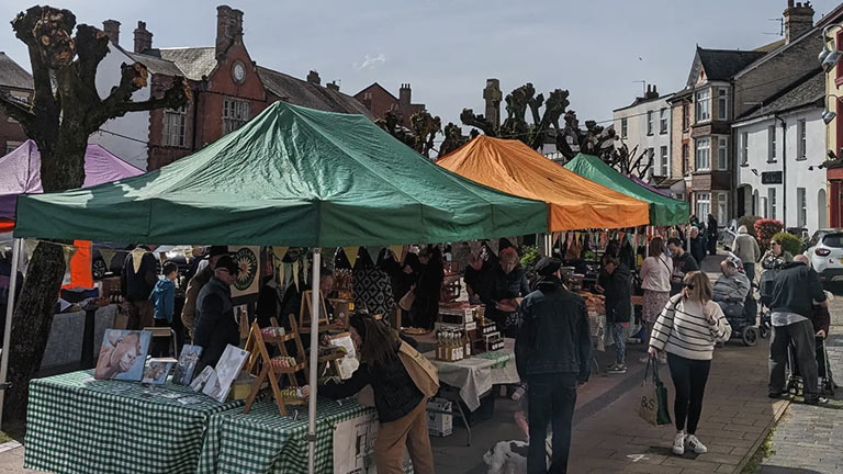 A view of the bustling Cullompton Farmers' Market with packed stalls and busy streets