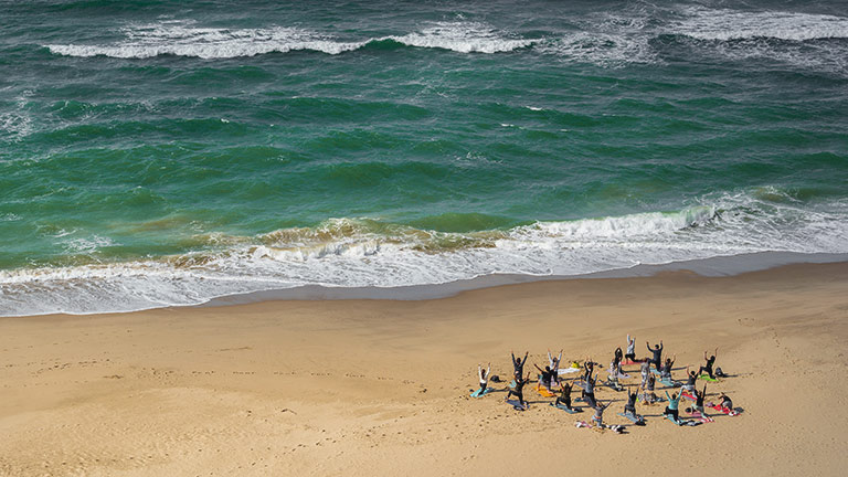 A group practicing  yoga by the shore on Alum Chine beach in Dorset