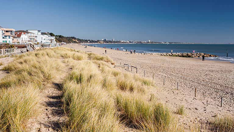 A view of the houses, sand dunes and sandy beach of Sandbanks in Dorset with the sea on a calm summer's day