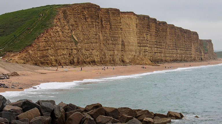 The golden cliff faces of West Bay in Dorset, with beach and sea below