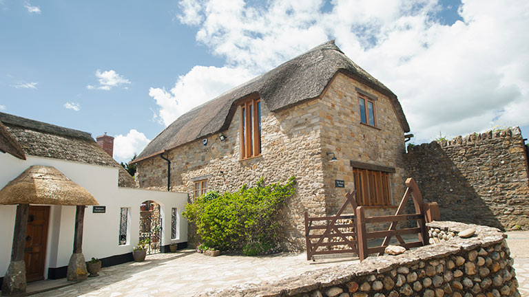 The thatched roof and picturesque stone façade of The Beach House homestay in Seaton