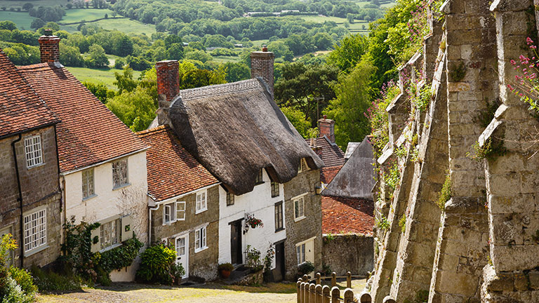 Cottages lining Gold Hill in Shaftesbury with countryside in the background