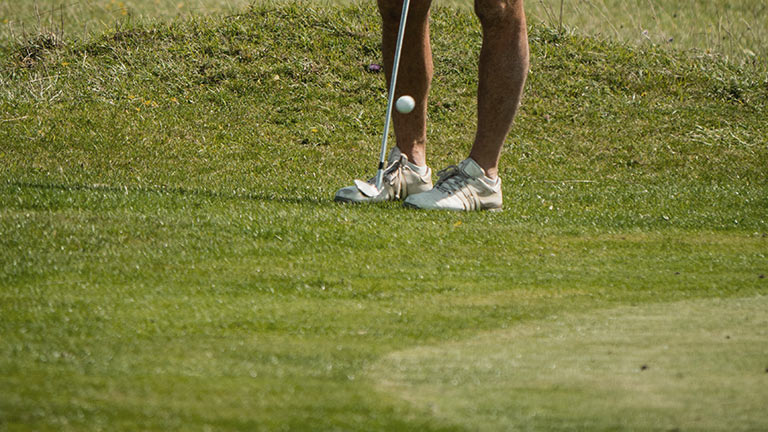 A person swinging a golf club on a grassy course