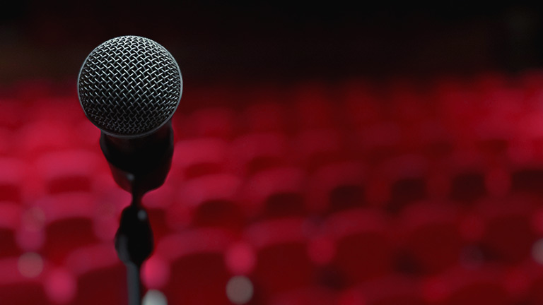 A mic with red theatre seats in the background