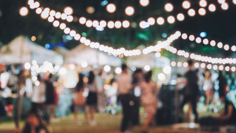 A pretty, blurred festival scene illuminated by fairy lights