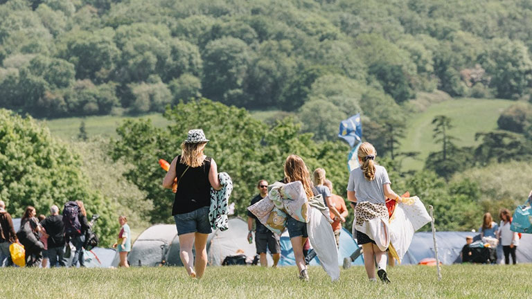 Festival goers walking through green fields at Wychwood Festival