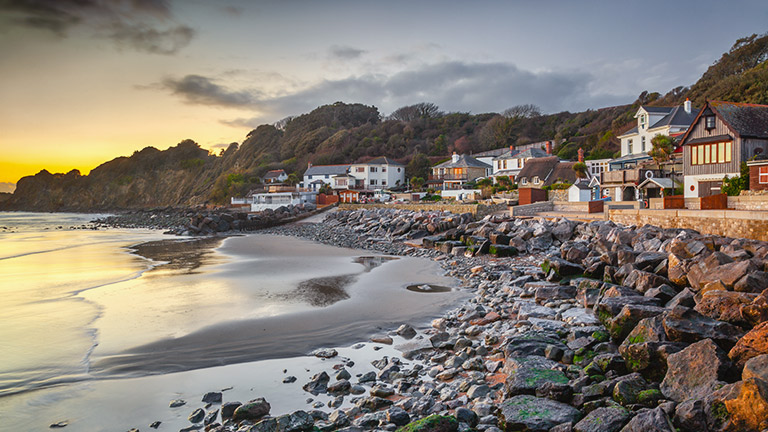 The rocky foreshore and sand of Steephill Cove overlooked by cottages