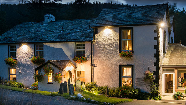 The illuminated exterior of Cottage in the Wood at night-time