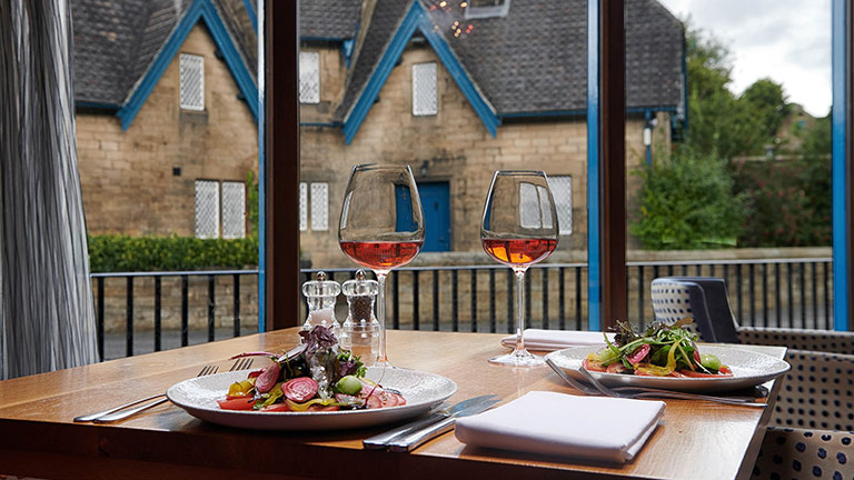 A windowside table and seats with food and drink at The Devonshire Arms in Beeley