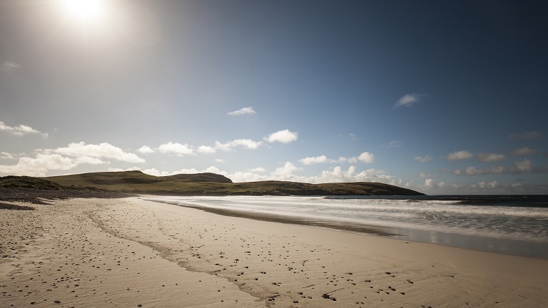 The stunning golden sand of Vatersay's coastline rolling towards the sea in the Hebrides