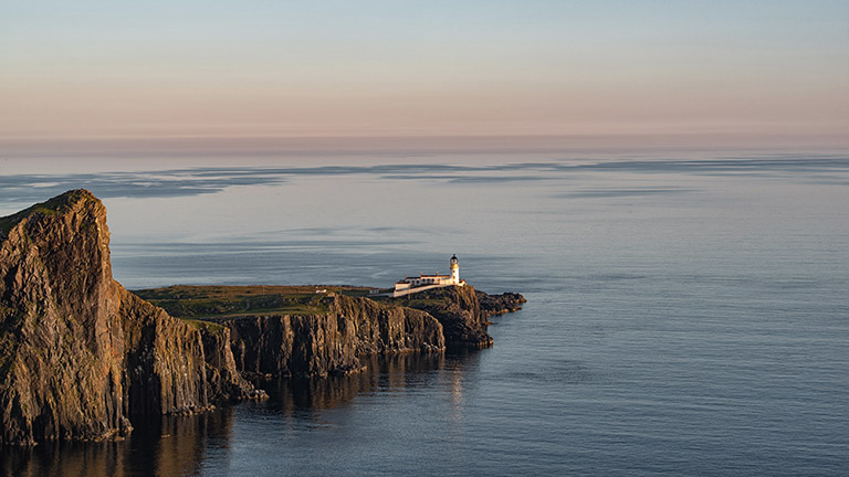 A distant view of Neist Point lighthouse in Skye on a balmy eve