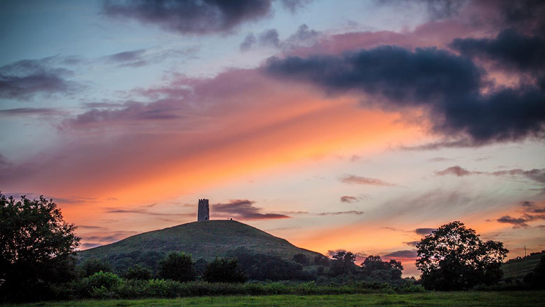 A view of St Michael's Tower atop Glastonbury Tor at sunset