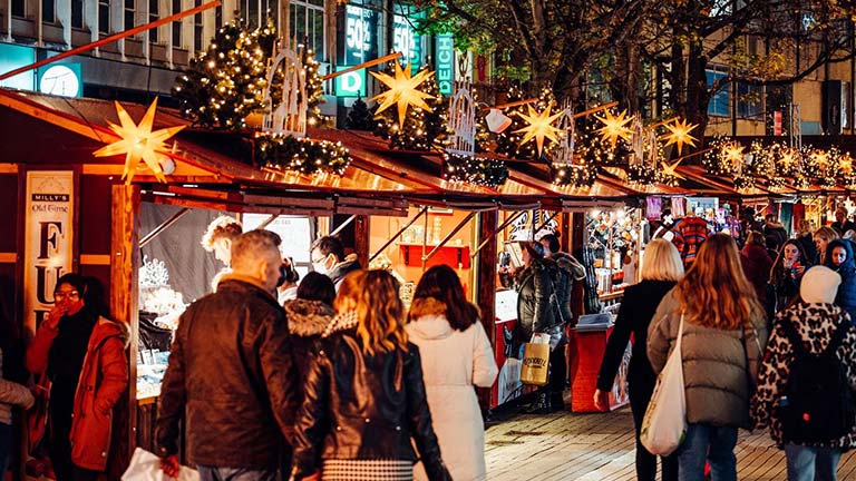 Wooden stalls filled with gifts and decorated with pretty Christmas lights at the Bristol Christmas Market Broadway