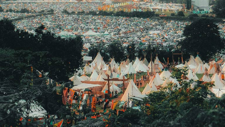 A view of Glastonbury Festival tipi tents through the trees 