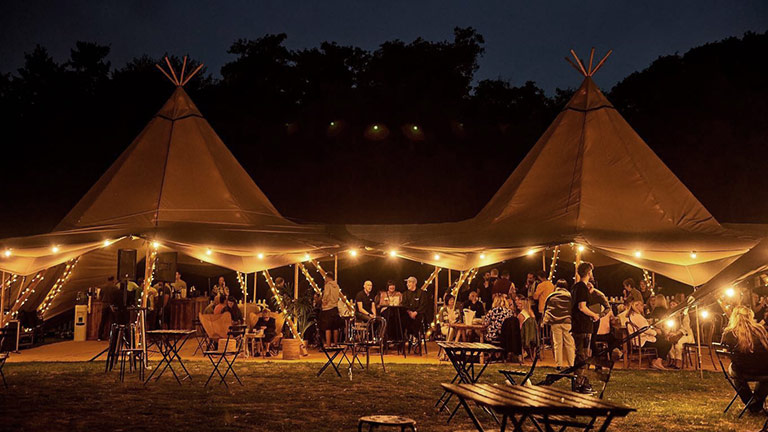 Food tents strung with fairylights at night at Pub in the Park festival 