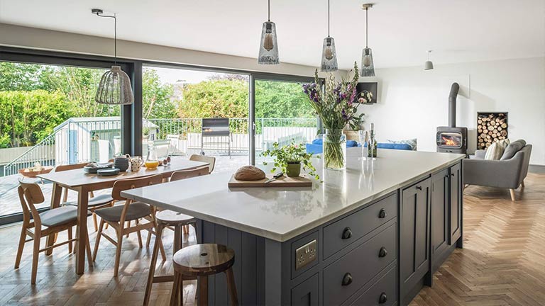 The bright and airy open plan kitchen at The Stables, with a big island counter in the centre of the room and windows overlooking the garden