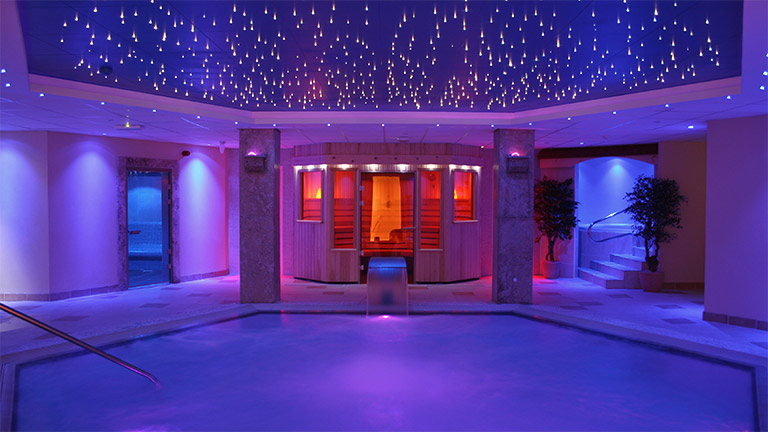 The swimming pool and sauna of Cliff Hotel Spa illuminated by ambient lighting and fairy lights