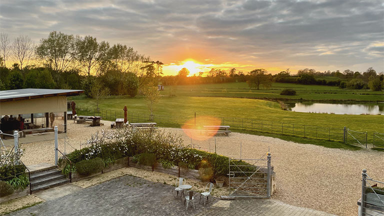 The outside seating area and manicured grounds of Wild Herb at the Field Kitchen in Wiltshire at sunset