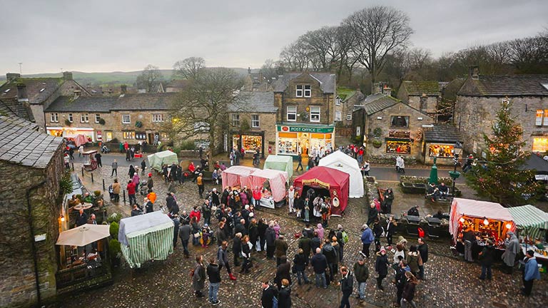 An aerial view of Grassington's Christmas Markets with Christmas stalls and festive shoppers