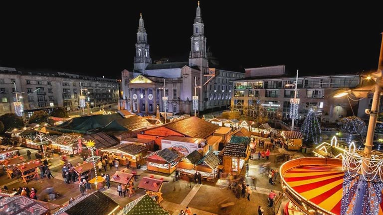 An aerial view of Leeds Christmas Market with traditional wooden cabins and fairground rides