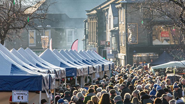 Crowds of festive shoppers milling along the high street during Skipton Yuletide Festival and Christmas Market